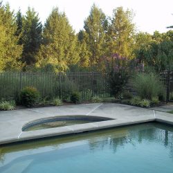 textured bronze aluminum pool fence installation protects a backyard pool