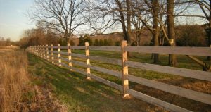 wooden modern fence design next to wild grass field and trees