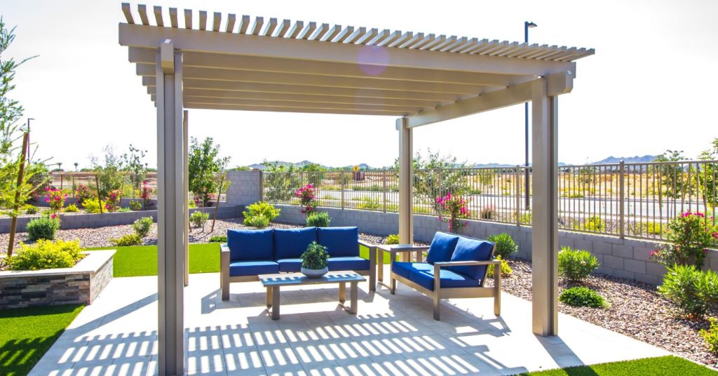 beige pergola for shade over small patio area with blue outdoor furniture underneath